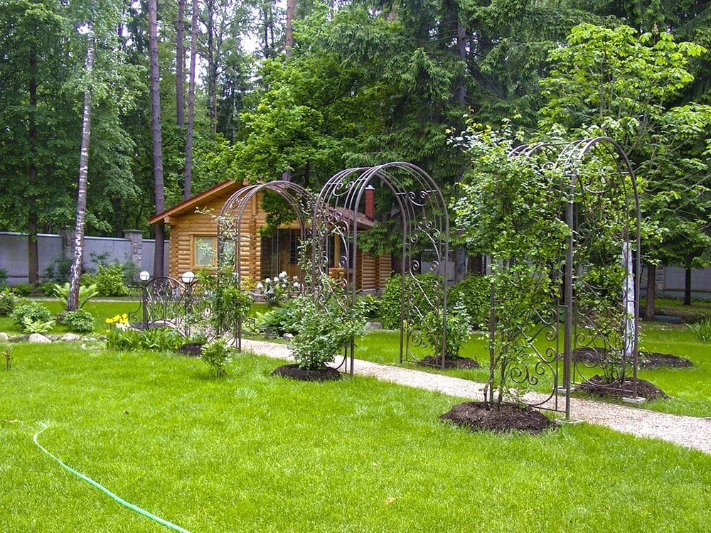 Садовая дорожка идет через арки-перголы с плетистыми розами